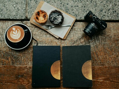 A few books, good food and a camera sitting on a table, capturing a perfect day of relaxation and creativity that awaits as long as we are willing to stop letting the digital world imprison us