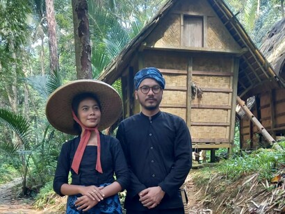 A pair standing before a traditional hut, symbolising the Baduy devotion to simplicity and natural materials