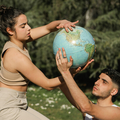 Una pareja posando con un globo terráqueo en un exuberante entorno natural, simbolizando la armonía, la coexistencia y la profunda conexión de la humanidad con la Tierra.