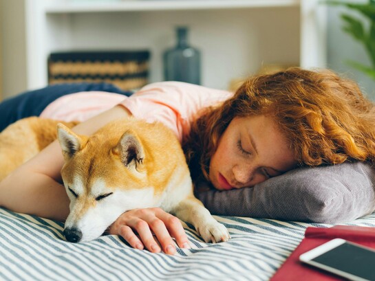 A woman dozing with her dog, capturing the simple, restorative power of pausing in a restless world