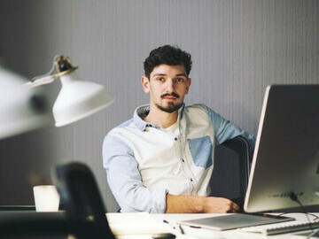 A young man working long hours on his laptop from home—highlighting remote work stress