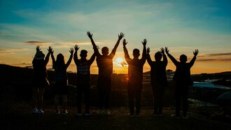 Silhouettes of people holding hands at sunset, symbolizing unity and togetherness
