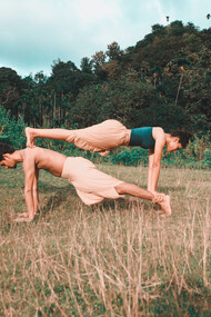 Casal de praticantes de yoga fazem uma posição desafiadora 