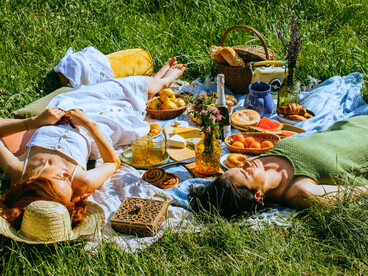 A group of women lounging on the grass during a picnic, enjoying unhurried time together
