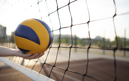 During a fast-paced rally, the ball strikes the net in a volleyball match, creating a moment of suspense as players prepare for the next move