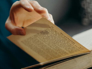 A close-up shot captures a person’s hands gently holding a book, evoking a sense of wisdom and lifelong learning