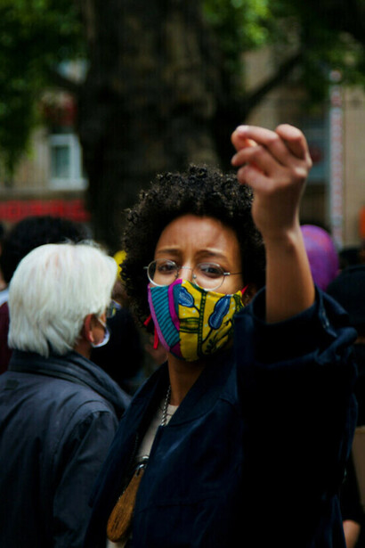 Una mujer con chaqueta negra y mascarilla amarilla protesta por la igualdad en Colonia, Alemania