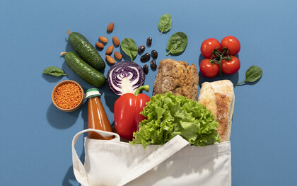 Una borsa della spesa in tela piena di prodotti freschi come verdure, frutta, pane e legumi