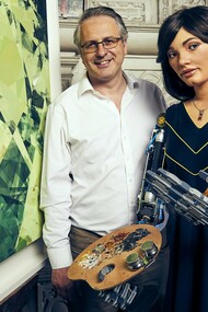 Ai-Da com o galerista Aidan Meller no Reino Unido, 2019. Há décadas, artistas programam algoritmos para criar imagens, sons e textos. Mas então, o que torna a obra de Ai-Da uma novidade?  A novidade não está no seu processo criativo, mas no espetáculo cuidadosamente construído ao seu redor