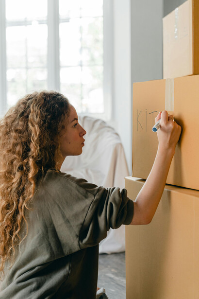 A woman packing boxes in her bedroom as she prepares to move to a new place and begin a fresh start