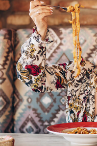 A woman savors delicious pasta in a cozy Italian restaurant, immersing in the ambiance of traditional dining