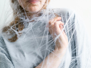 A woman’s body entangled in web-like strands, representing how the human psyche traps itself in fear-driven interpretations