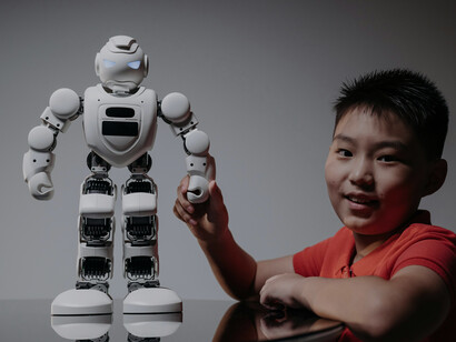 A child watching a white toy robot closely