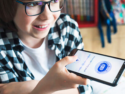 A smiling boy chatting with an AI chatbot on his mobile, illustrating how AI transforms digital experiences