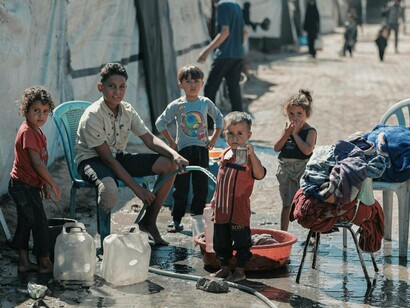 Homeless children collecting water, representing the daily burden of resource scarcity in vulnerable communities