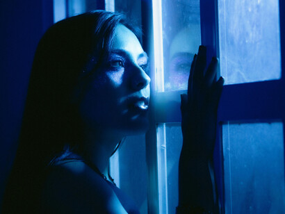 Elle regarde dehors, mais c’est en elle que la jalousie s’étire, froide et bleutée, comme un horizon inaccessible