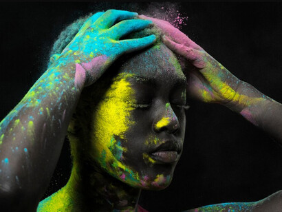 A thoughtful model with colorful powder on his face, eyes closed in quiet meditation and silent reflection