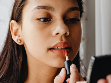 A young woman adds the final touch to her look, applying lipstick with care