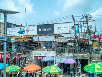 Des panneaux publicitaires colorés surplombent le marché central de Lagos, symbole des échanges commerciaux florissants et de la résilience des habitants face aux tensions régionales