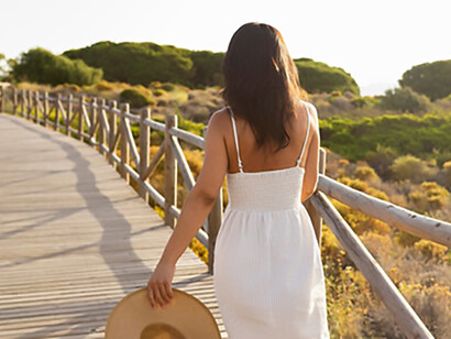 A woman in nature, seen from behind with a hat, symbolizes a healing journey, standing strong in spiritual warfare as she embraces peace and renewal