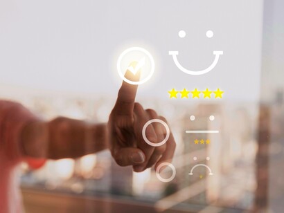 Dito che clicca sulla faccina sorridente: l'immagine cattura il gesto diretto e intuitivo del cliente che seleziona la sua valutazione