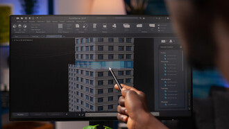An architect engineer analyzing a construction model on a computer, pointing at an architectural building prototype