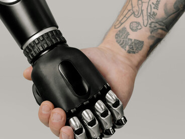 A human hand reaches out to touch a robotic hand, symbolizing the connection between humans and AI