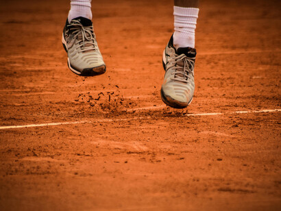 A view of a player's shoes and the clay surface