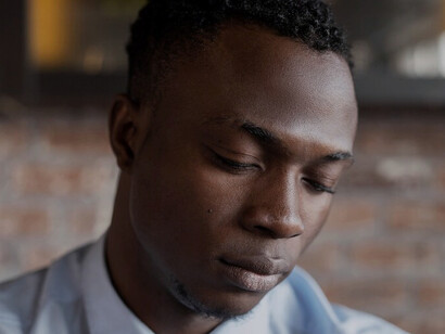 His sorrowful gaze highlights the crisis of masculinity, where societal expectations create isolation and emotional disconnection, leading to profound mental health challenges