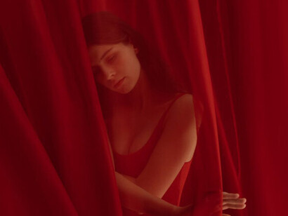 The vibrant red of her jumpsuit mirrors the passion and complexity of sexuality often hidden behind a veil of silence