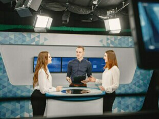 A TV presenter and two participants in the studio, preparing to answer questions for an upcoming broadcast, showcasing the dynamic environment of television media