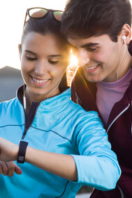 Young couple using their smartwatches to track fitness data post-run