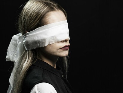 Mulher angustiada, com olhos vendados. Em certas circunstâncias, preferimos trocar a dor aguda de enfrentar uma situação, pela dor crônica de conviver eternamente com o problema. E aí só nos resta esconder o sofrimento, tentar ignorá-lo, aprender a conviver com ele, passar aos outros a aparência de que ele não existe e remoer solitariamente o martírio. 
Isto pode até não nos levar à morte, mas tem chance de tirar a alegria de nossa vida, o que é quase o mesmo. Buscamos refúgio e encontramos prisão