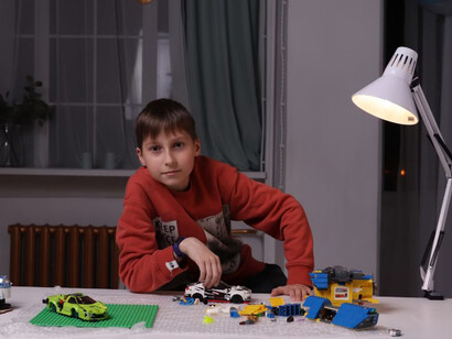 A young boy builds with LEGO bricks on the table, immersed in his play