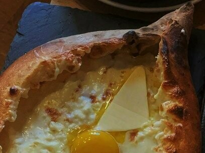 O famoso Khachapuri, uma espécie de esfiha em formato de canoa, assada na hora e com recheio de queijo. Por cima, vem um pouquinho de manteiga derretendo e uma gema, que ela explicou que deveríamos misturar pra cozinhar com o calor do queijo e depois ir tirando pedaços da massa e comendo junto com esse recheio. Estava perfeito! Depois chegou uma espécie de ensopado com pedaços de frango imersos num molho claro, à base de coalhada e que acompanha um pãozinho. Estava divino! 

