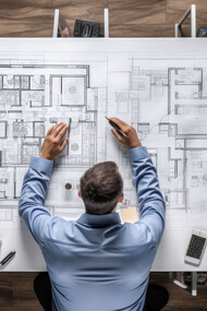 Architect meticulously crafting a blueprint at his office desk, exemplifying precision and dedication in architectural design