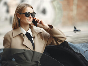 A woman in elegant neutral tones standing near a sleek car, reflecting the understated sophistication and effortless grace of quiet luxury
