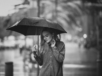 A woman walking alone down the street holding an umbrella