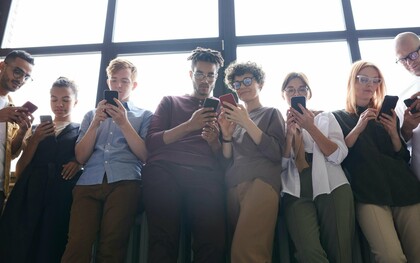 Un groupe de jeunes adultes fait défiler leurs téléphones, inconscients de leur environnement