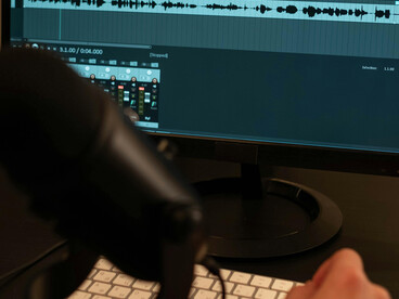 A person pointing at a screen while giving voice commands in an interactive audio installation