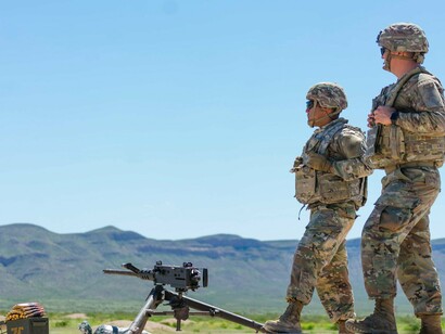 Soldiers patrolling and standing near a weapon, symbolising readiness and vigilance in the face of potential threats