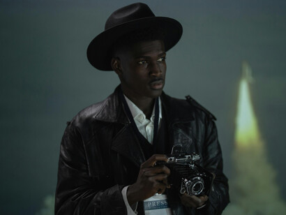 A journalist with a camera in dark attire, reflecting the dangers and pressures of access reporting