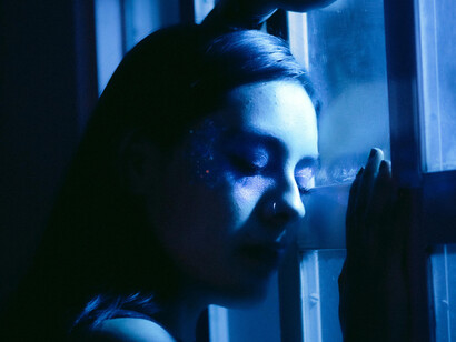 La fenêtre sépare le monde et le manque ; sous la lumière nocturne, la jalousie devient un murmure immobile