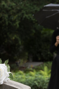 A young woman in a graveyard holding a white rose
