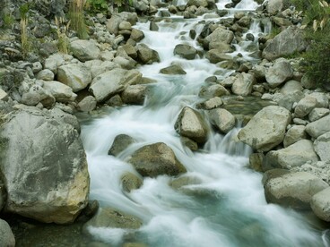A steady current over stones mirrors the slow, enduring work of rebuilding trust among nations