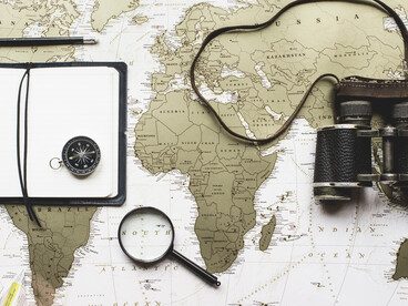 A vintage world map centred on Africa surrounded by navigation tools, representing the long history of exploration, colonial ambition, and geopolitical interest in the continent