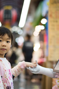 A photo of a girl resting her left hand on a white digital robot in Japan