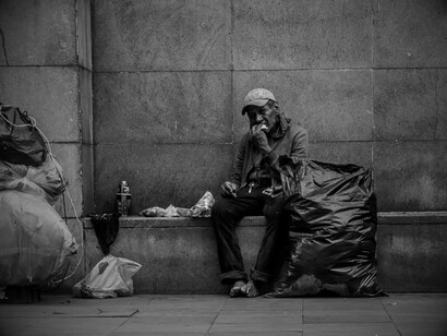 Dans l’ombre des politiques d’austérité, des millions de vies basculent dans la précarité, ici figée dans une rue où la survie tient dans quelques sacs