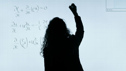 A woman writing on a whiteboard during a university lecture