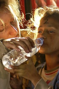Soldier gives a drink of water to a child refugee